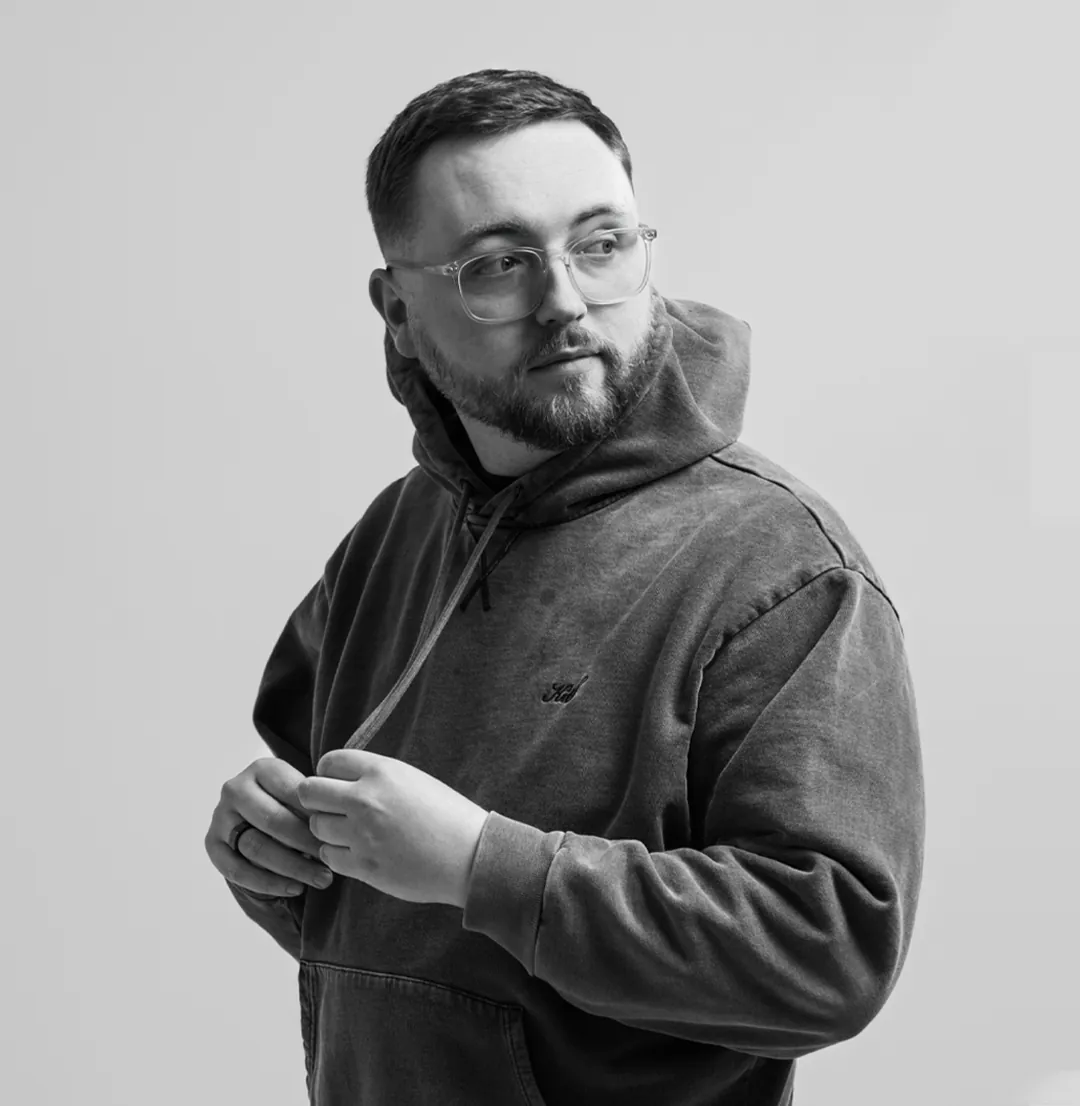 Gannon Meyer in a dark hoodie and clear glasses, black and white portrait